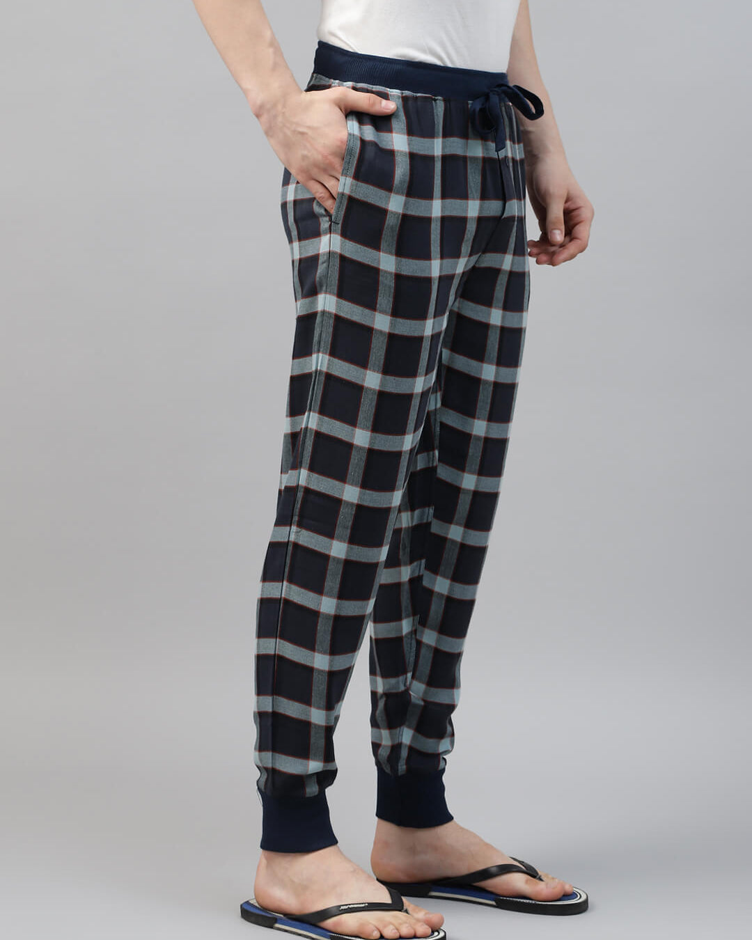 Person wearing black and white plaid jogger pants on a gray background