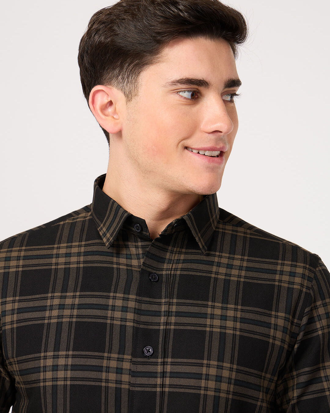Man wearing a black and brown plaid shirt against a white background