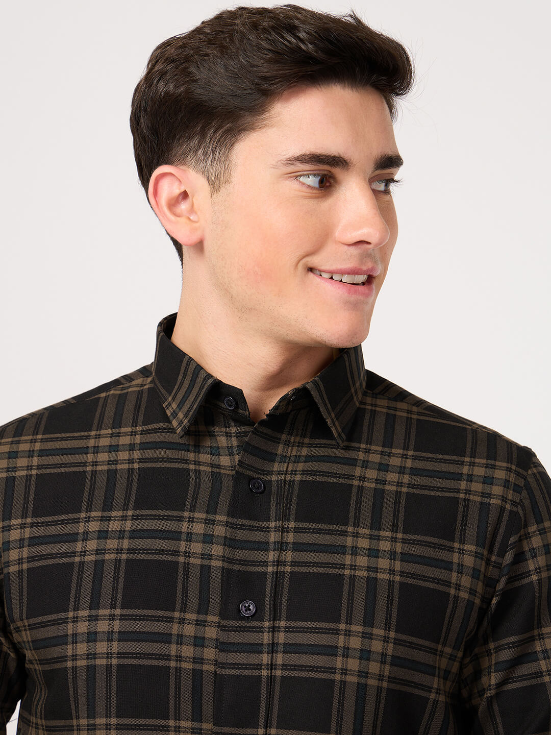 Man wearing a black and brown plaid shirt against a white background