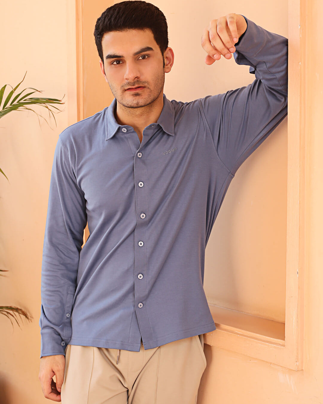 A man wearing a grey knit cotton shirt and beige pants