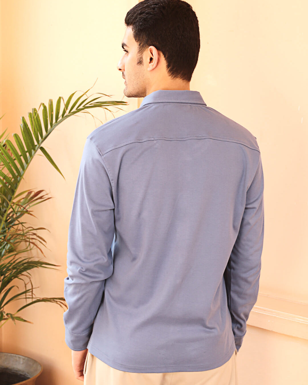 A man wearing a grey knit cotton shirt and beige pants