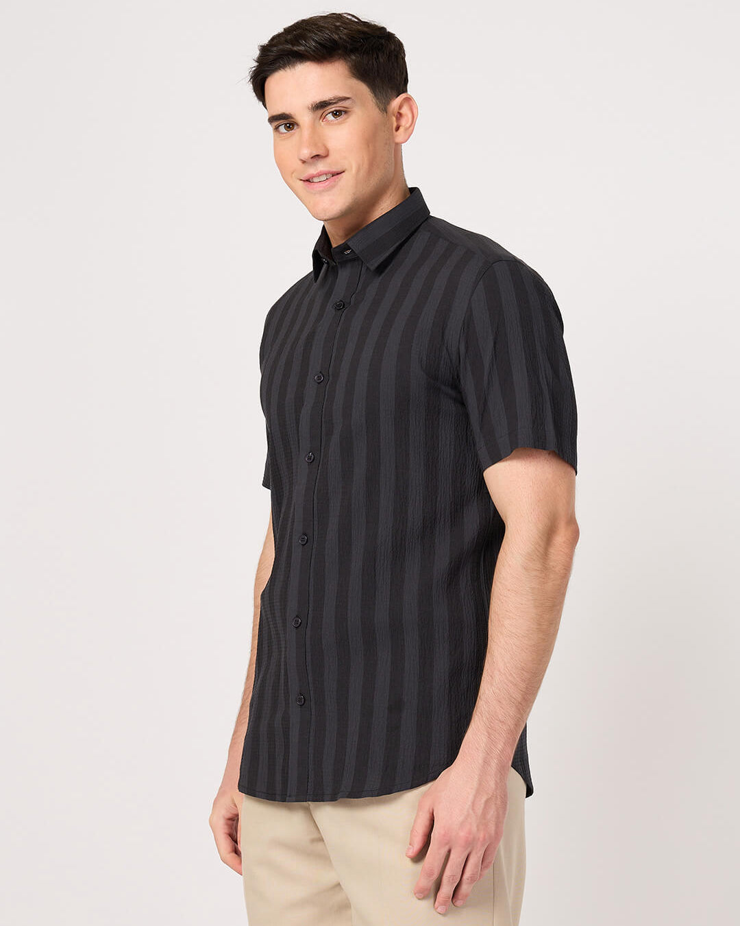 A man wearing a striped half sleeve shirt with beige pant.