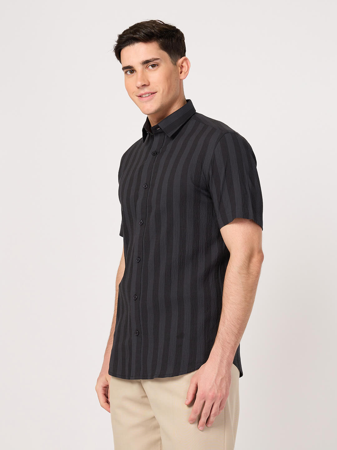 A man wearing a striped half sleeve shirt with beige pant.
