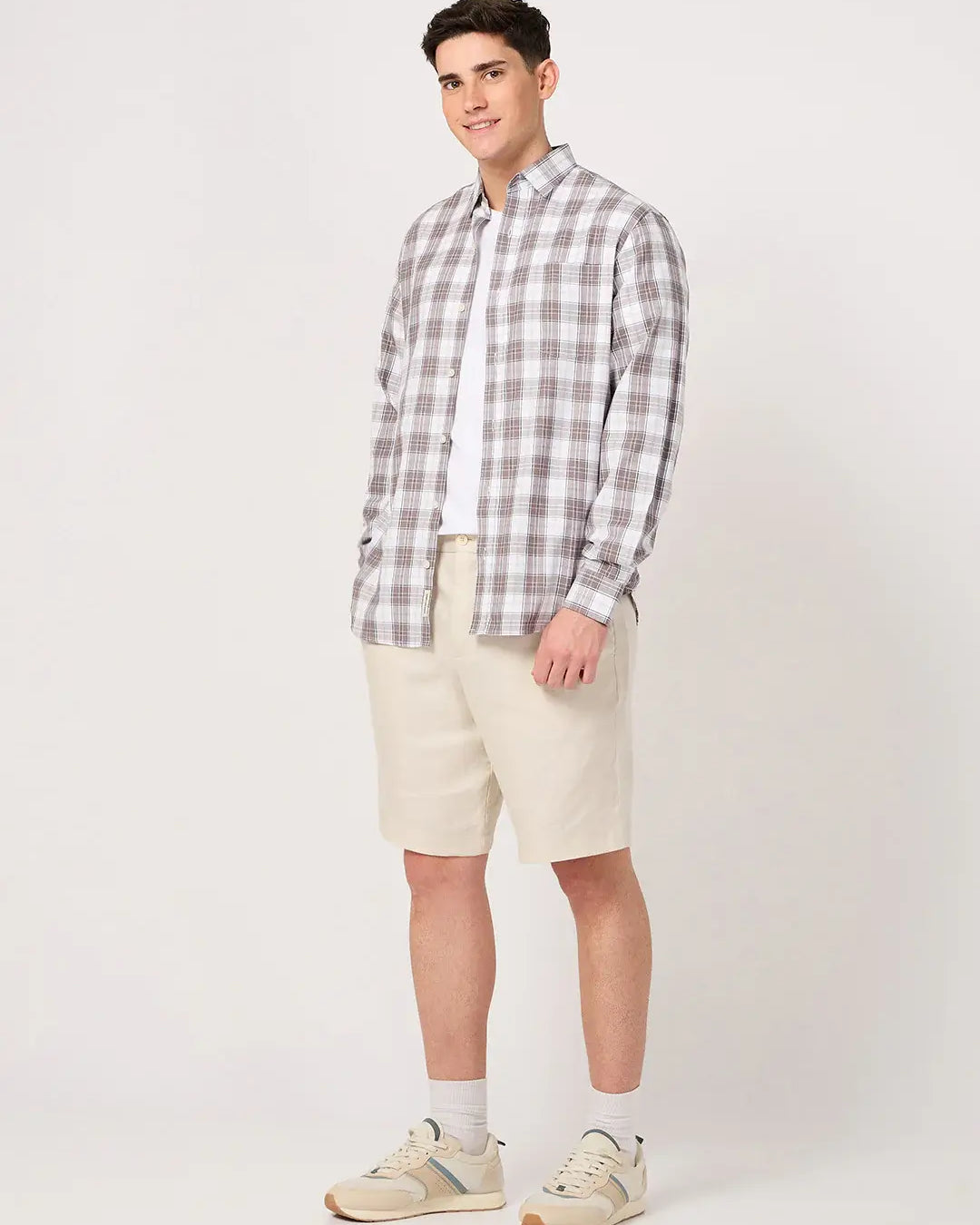 Man wearing a brown and white check shirt and beige shorts