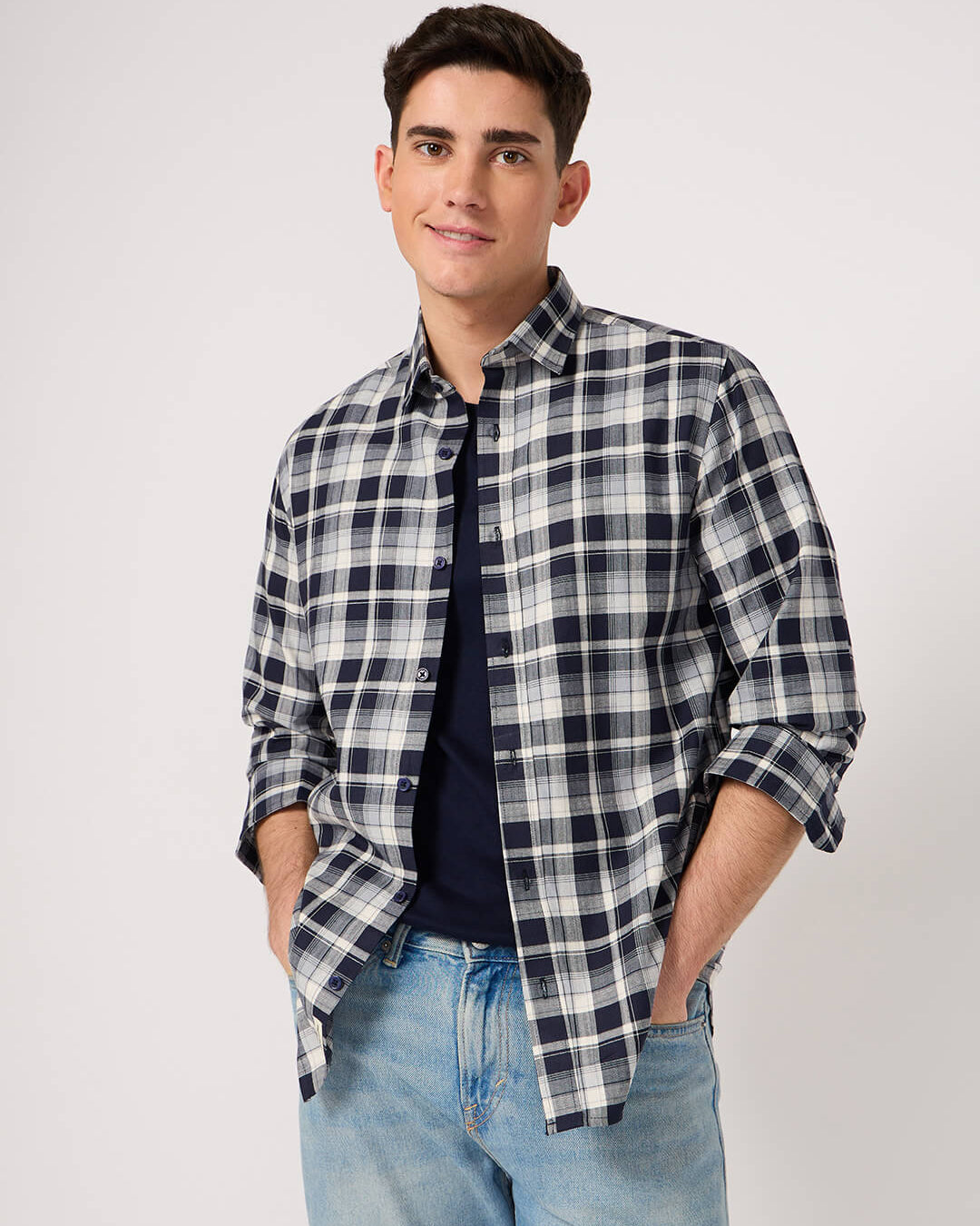Man wearing a plaid shirt and jeans on a plain background