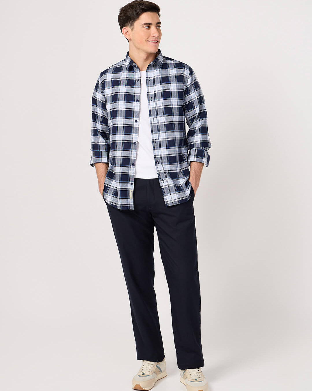 Man wearing a blue and white plaid shirt with dark pants on a white background