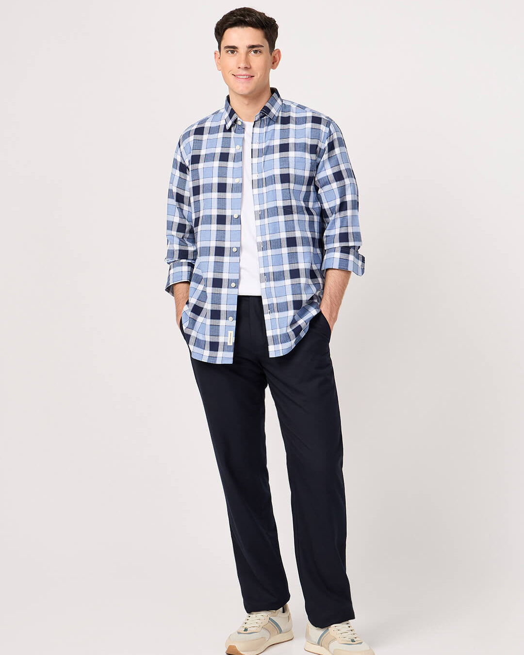 Man wearing a cotton blue check shirt and dark pants on a white background