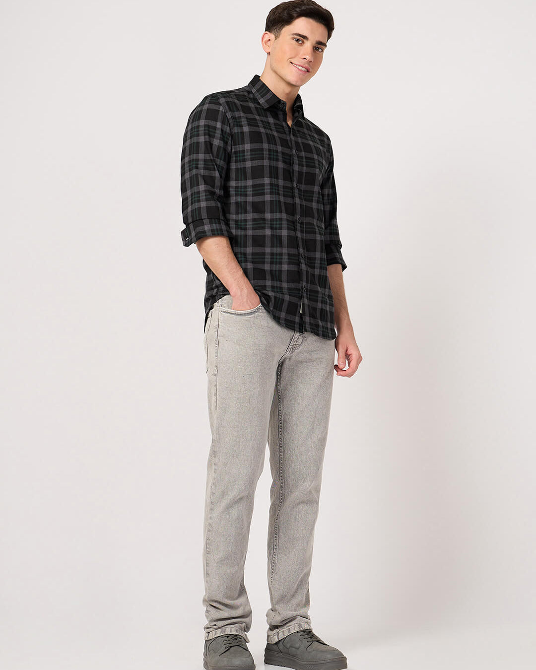 Man wearing a black and gray plaid shirt with gray pants on a white background