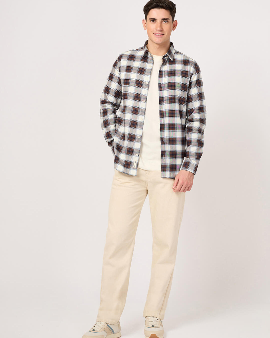 Man wearing a plaid shirt and beige pants on a white background