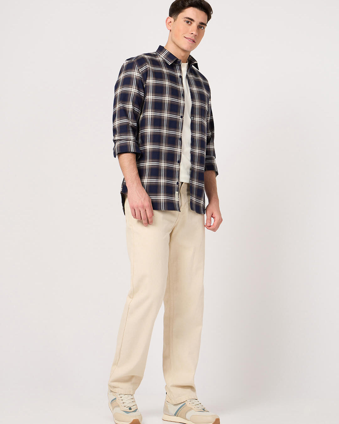 Man wearing a cotton check shirt and beige pants on a white background