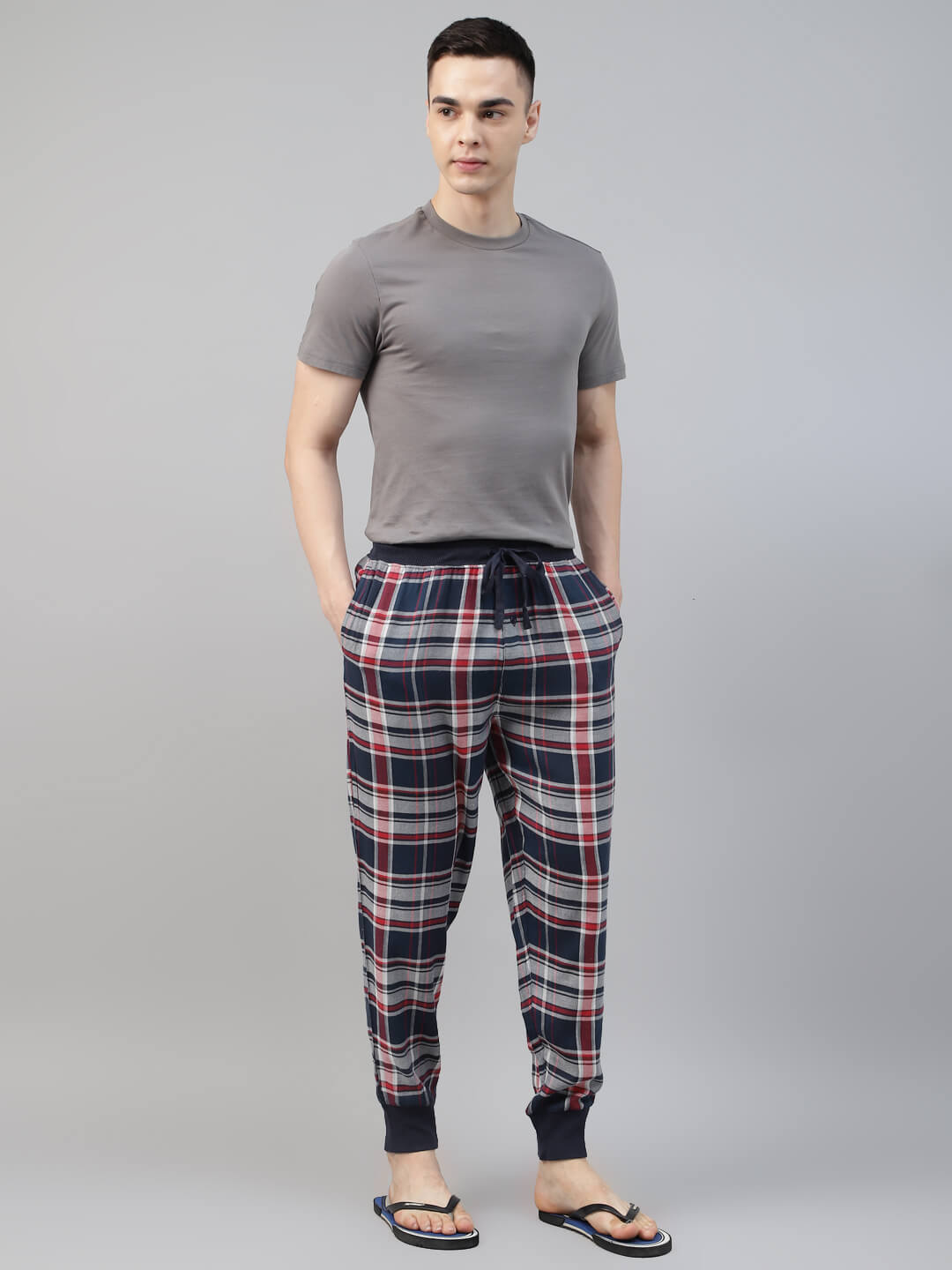 Man wearing a gray t-shirt and plaid jogger pant on a gray background