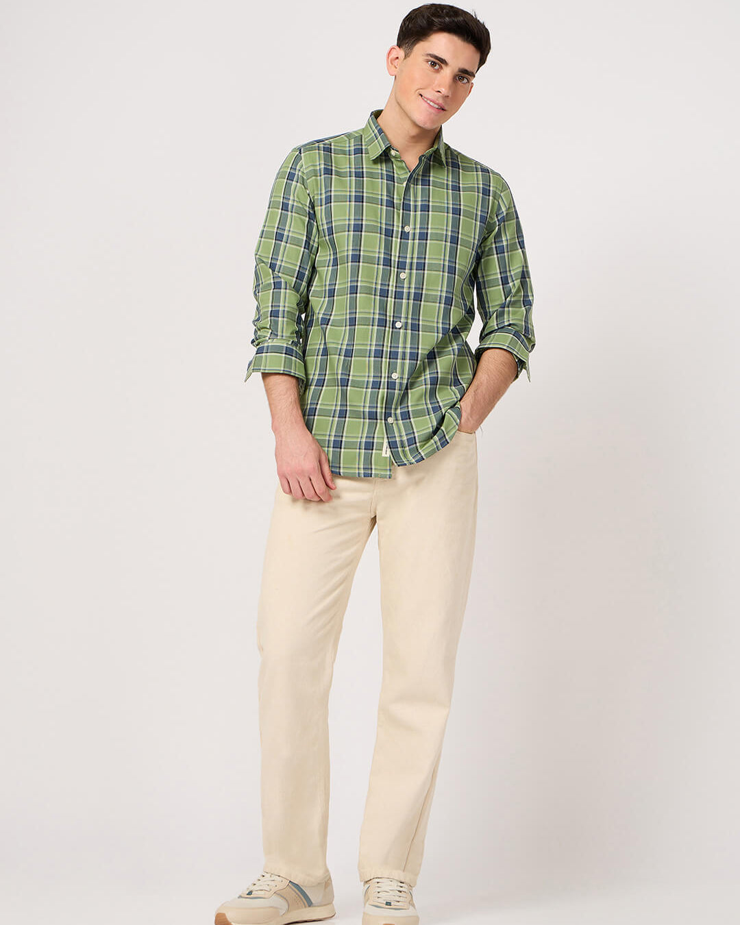 Man wearing a green plaid shirt and beige pants on a white background