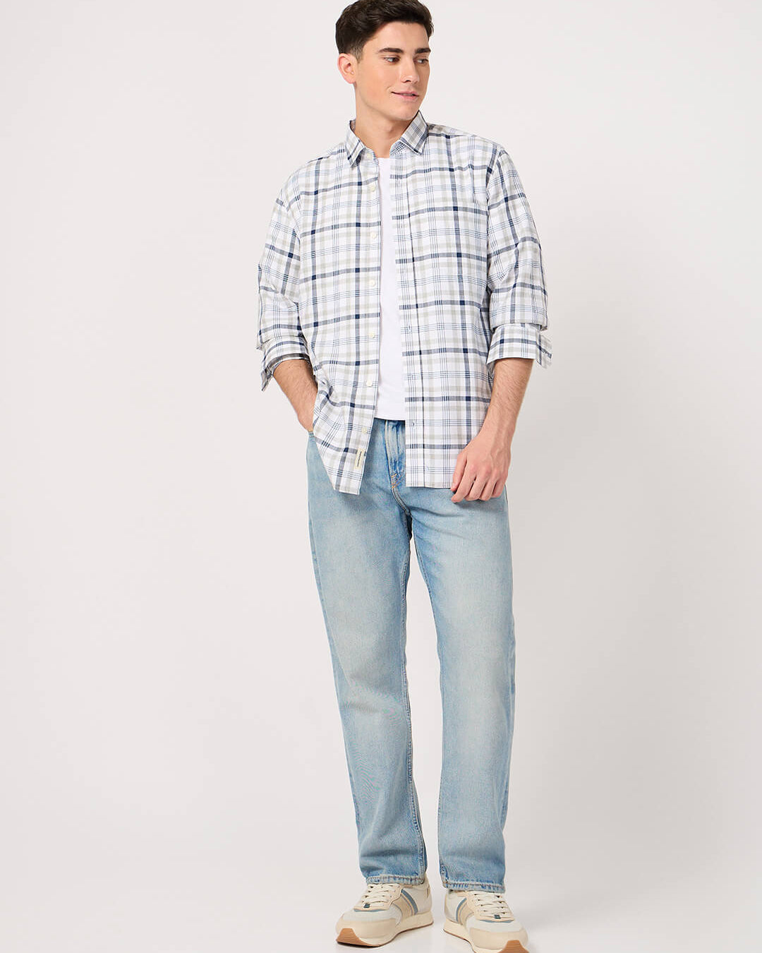 Man wearing a check cotton shirt and light blue jeans on a white background