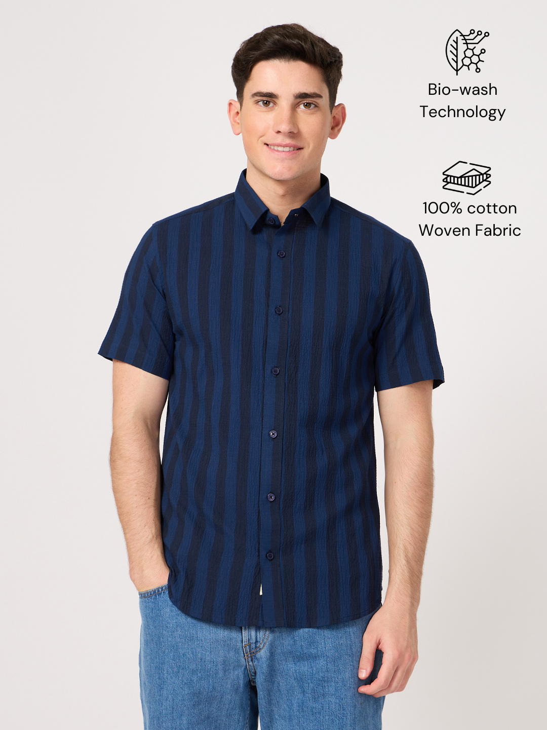 A man wearing a blue striped cotton half sleeve shirt with a collared neckline, paired with blue jeans.