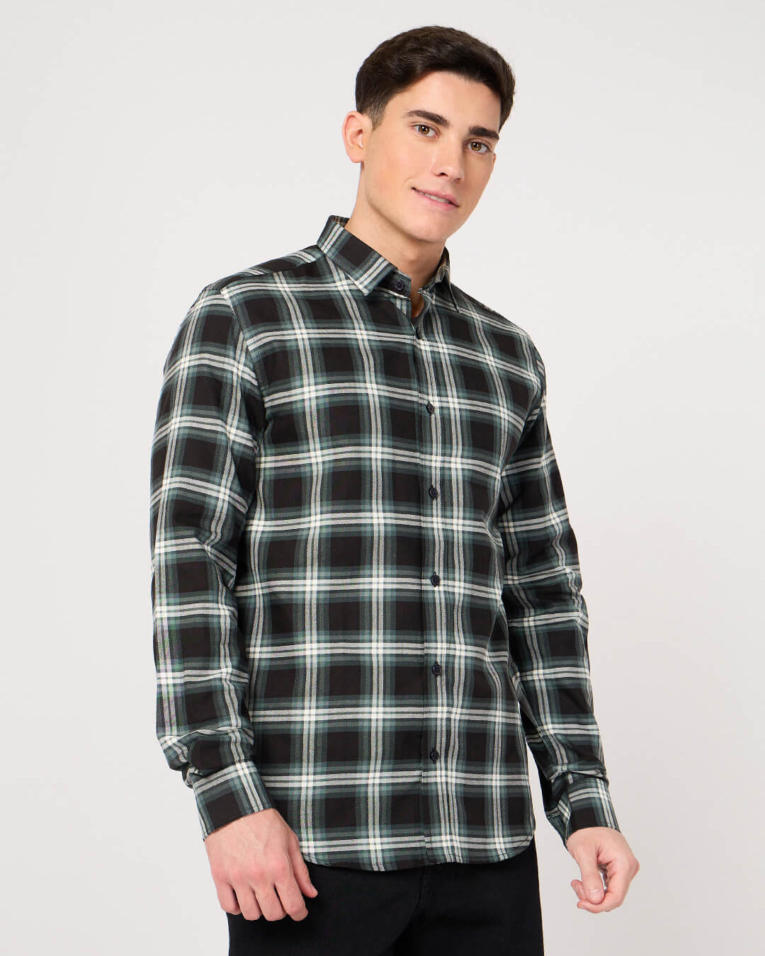 Man wearing a black and green plaid shirt on a white background