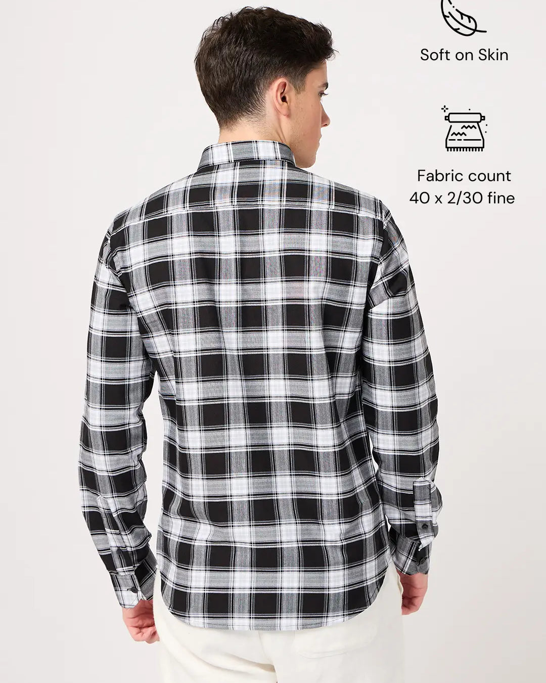Person wearing a black and white checkered shirt with fabric details on a light gray background
