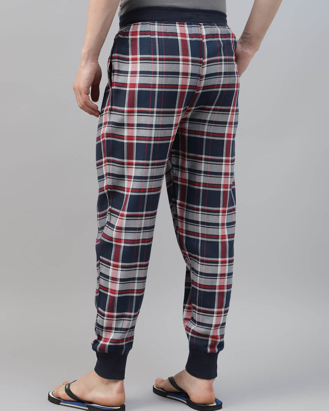 Plaid pajama pants worn by a person on a gray background