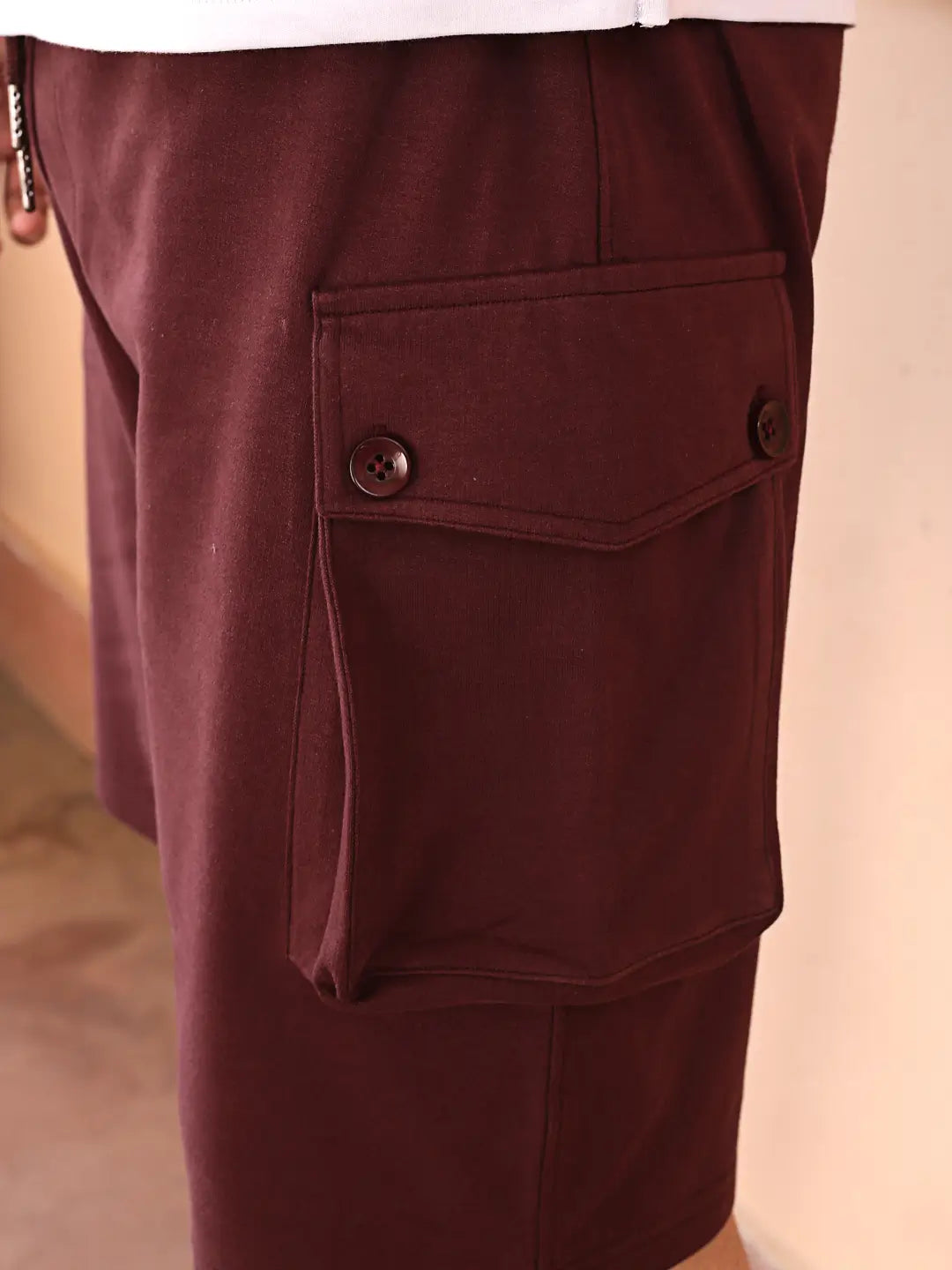 Close-up of maroon shorts with a pocket on a neutral background