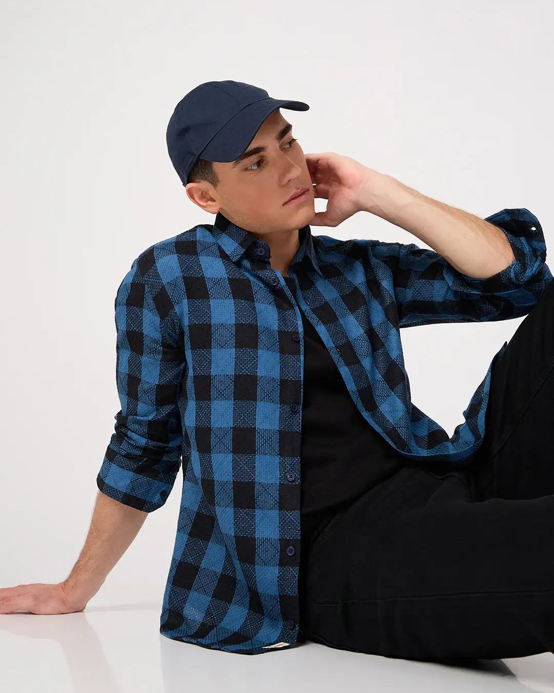Person wearing a blue and black checkered shirt and cap