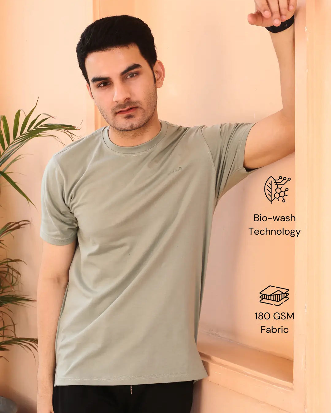 Man wearing a light gray crew neck cotton t-shirt, standing against a beige wall.