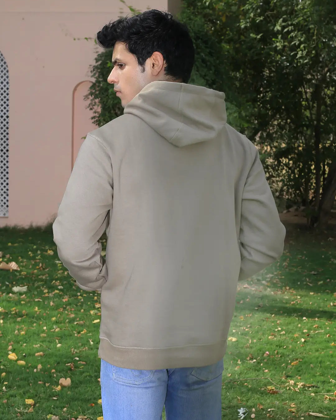 Person wearing a grey hoodie and blue jeans standing outdoors