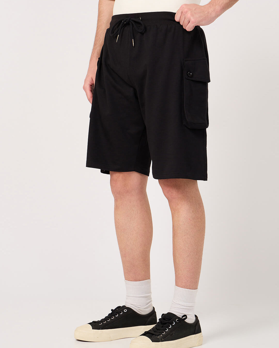 Person wearing black cargo shorts on a white background