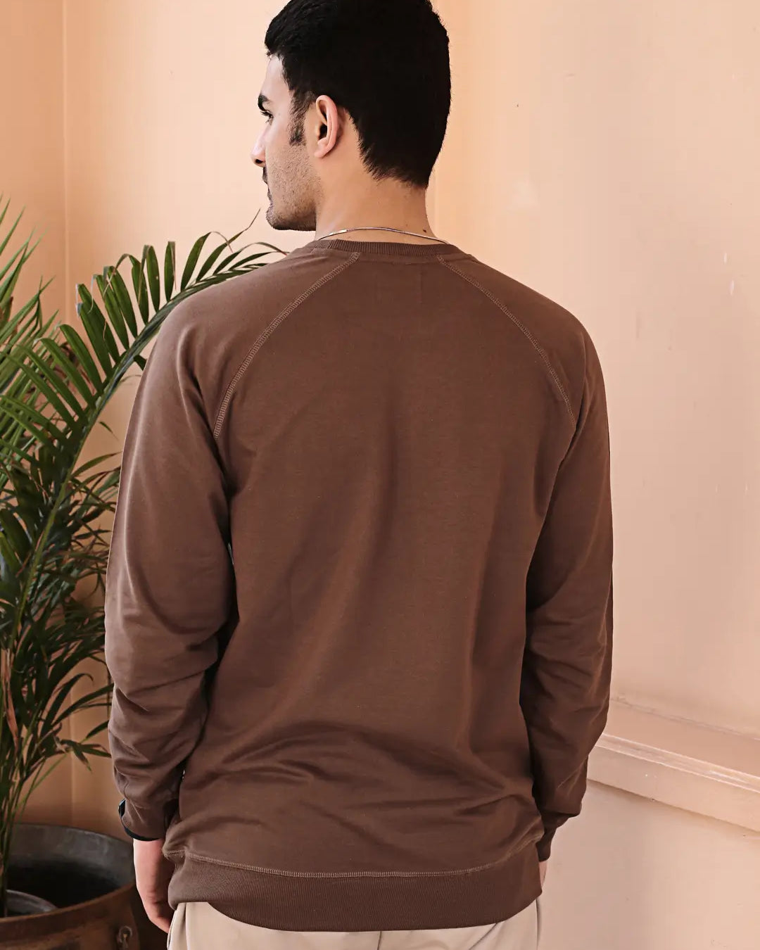 Man wearing a brown sweatshirt standing in a room