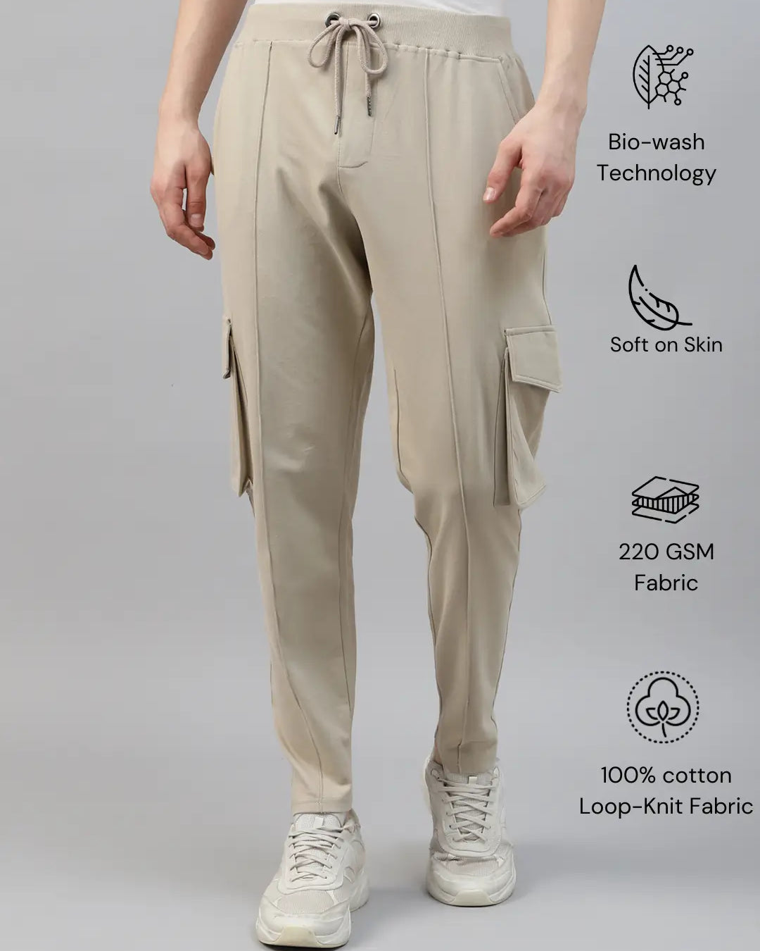Beige cotton cargo pants worn by a person on a gray background