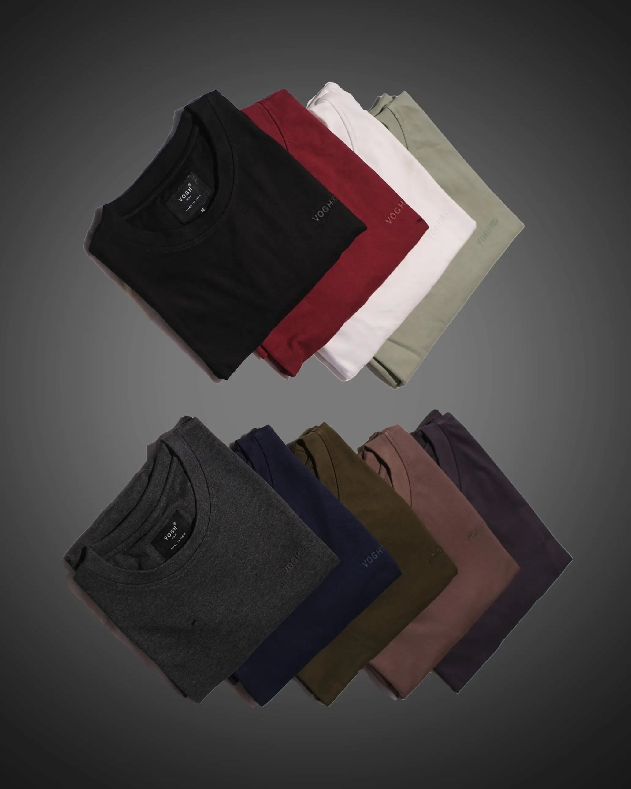 Folded t-shirts in various colors on a gray background