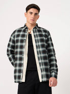 Man wearing a black and green plaid shirt over a black t-shirt on a white background