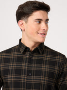Man wearing a black and brown plaid shirt against a white background