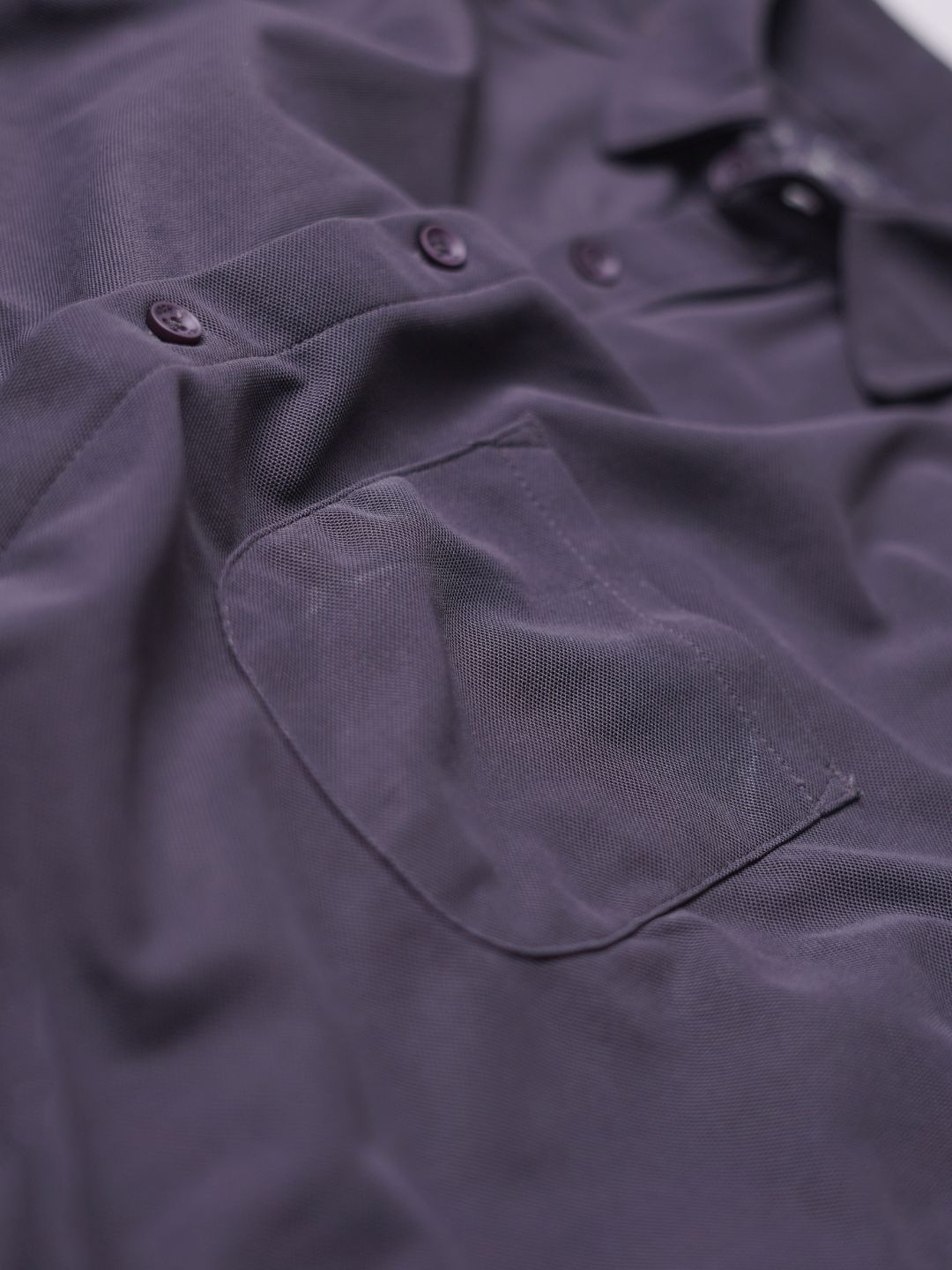 Close-up of a dark purple shirt with buttons and a pocket