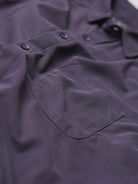 Close-up of a dark purple shirt with buttons and a pocket