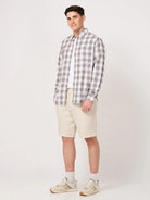Man wearing a brown and white check shirt and beige shorts