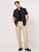 A man wearing a striped half sleeve shirt with beige trouser