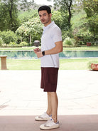 Man wearing a light sky blue polo shirt and maroon shorts