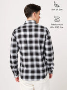 Person wearing a black and white checkered shirt with fabric details on a light gray background
