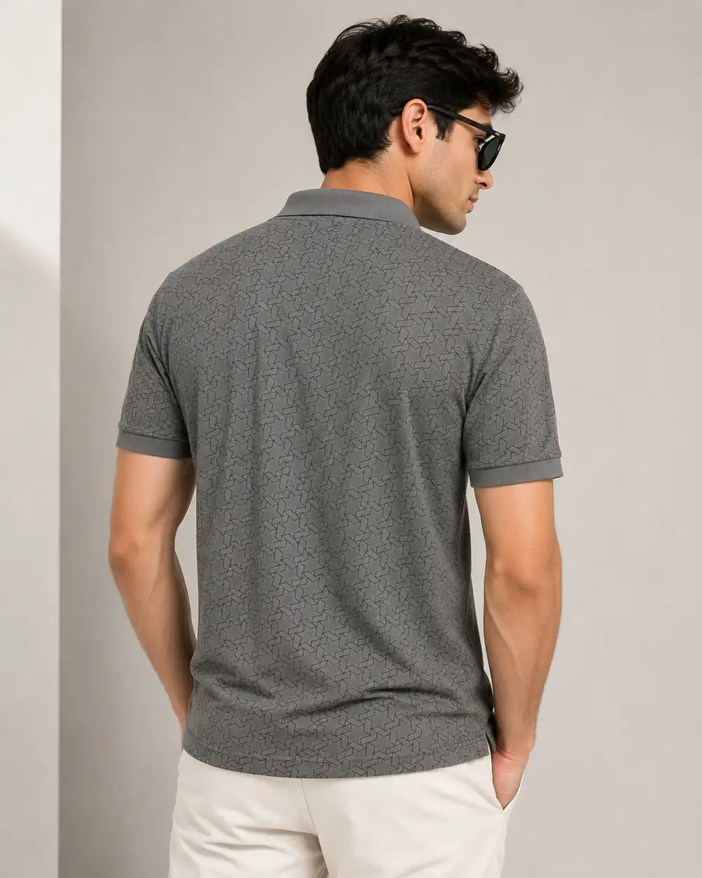 A man wearing a dark gray short-sleeve polo t-shirt with a subtle geometric pattern