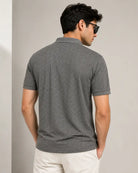A man wearing a dark gray short-sleeve polo t-shirt with a subtle geometric pattern