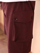 Close-up of maroon shorts with a pocket on a neutral background