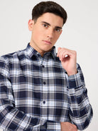 Man wearing a blue and white plaid shirt against a plain background