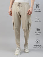 Beige cotton cargo pants worn by a person on a gray background