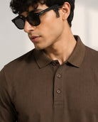 A man wearing a vogh brown ribbed polo shirt
